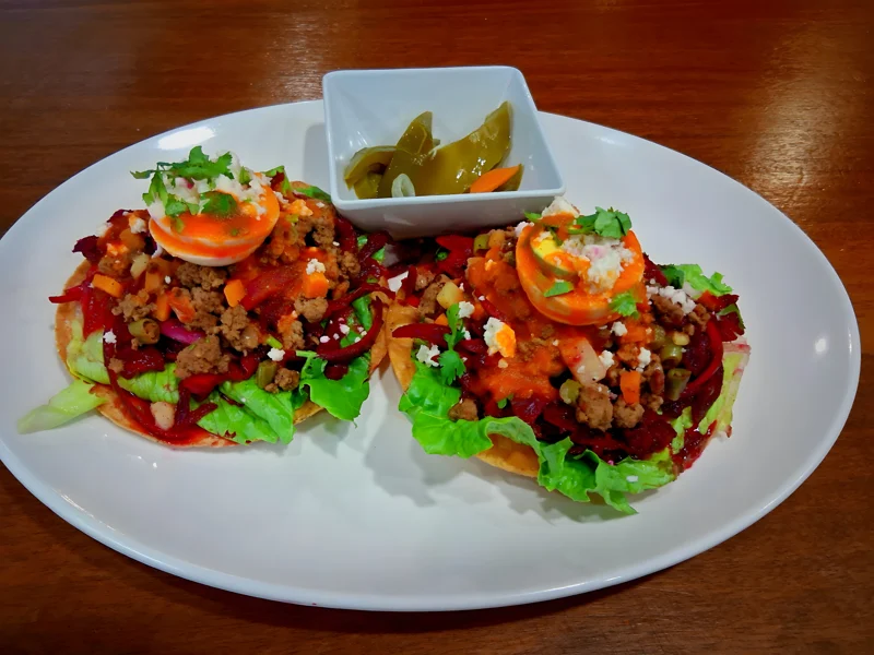 Two portions with vegetable toppings on a white platter